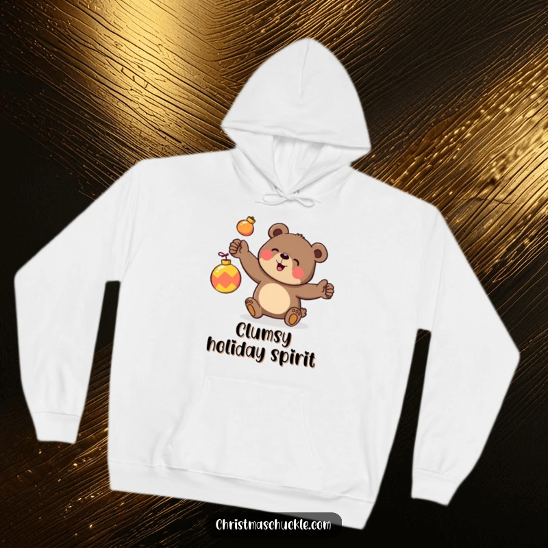 Funny hoodie graphic of a happy bear character clumsily juggling three brightly colored ornaments, designed for cozy holiday cheer.